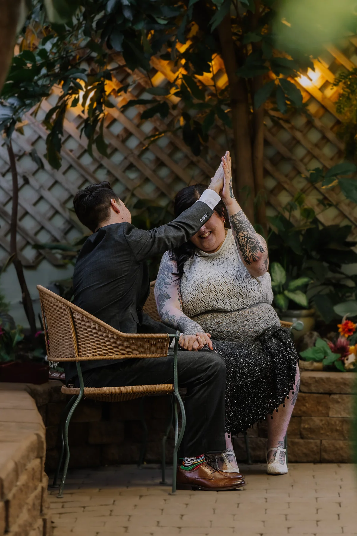 Couple sharing a high-five on a garden bench, candid and joyful