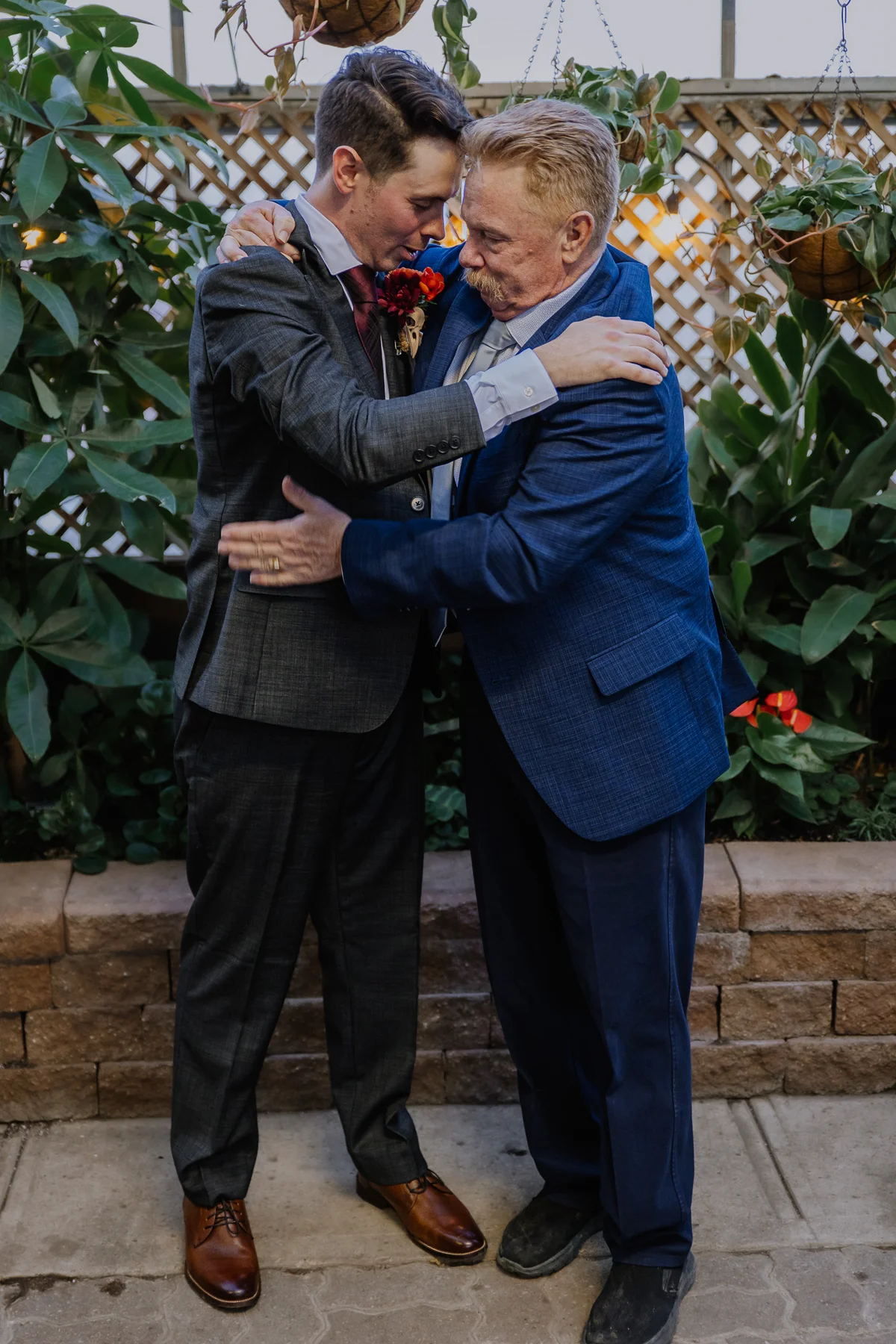 Groom holding his father close in the greenhouse, an intimate post-ceremony hug