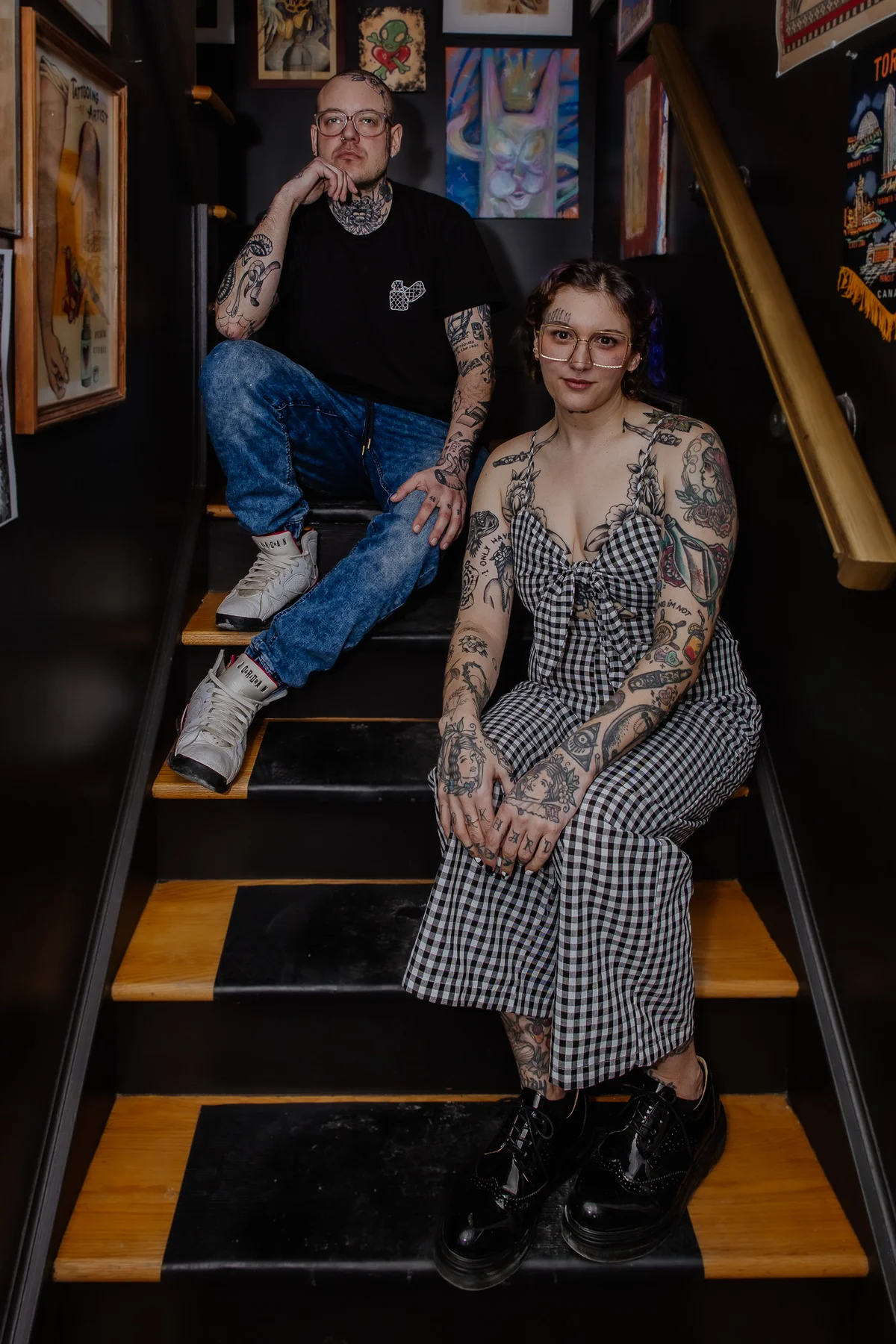 Branding portrait, two tattooed subjects seated on a stairwell, confident and deliberately styled